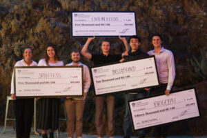 A group of students smiling and holding giant checks